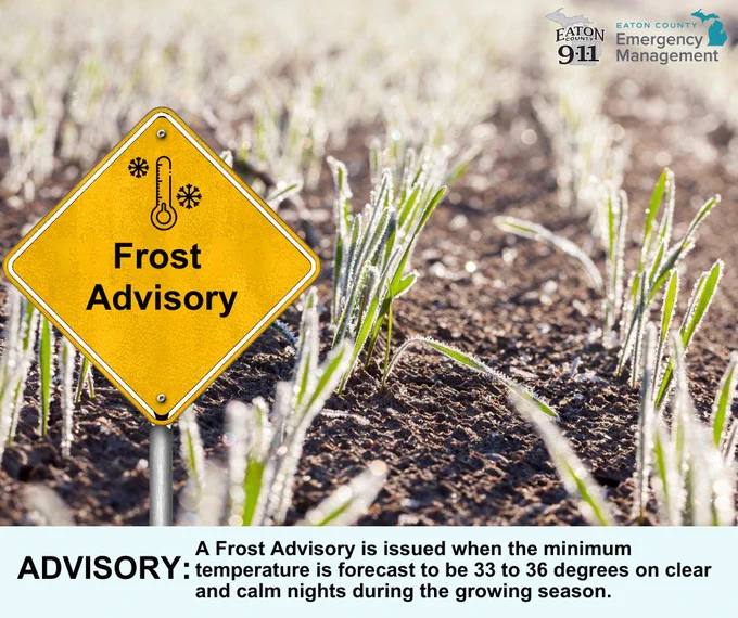 A yellow road sign reads "Frost Advisory". In the background, green crops grow in a frost-covered field under early morning light. A caption at the bottom reads "ADVISORY: A Frost Advisory is issued when the minimum temperature is forecast to be 33 to 36 degrees on clear and calm nights during the growing season."