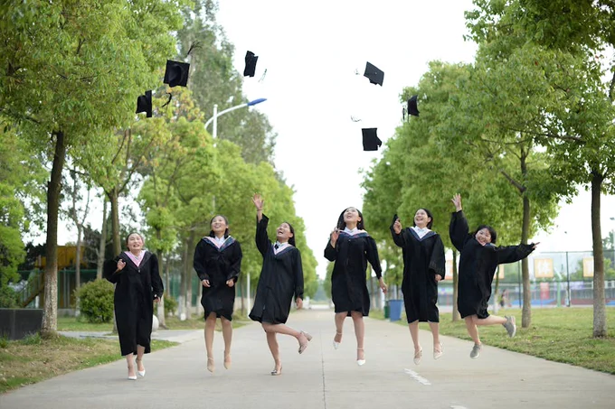Graduates celebrating by tossing caps in the air on a bright day.