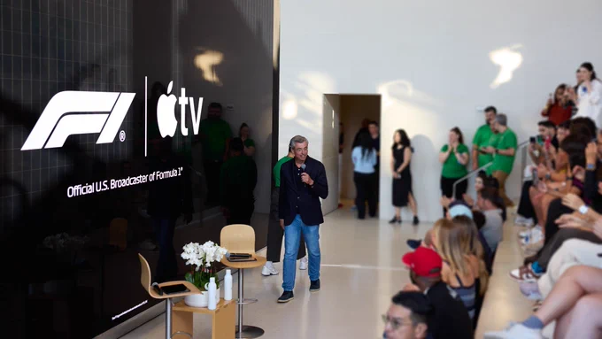 Eddy Cue walks in front of a crowd holding a microphone.