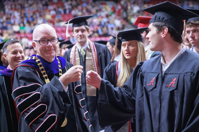 President Mohler is seen giving a fist bump to a graduate at Commencement.
