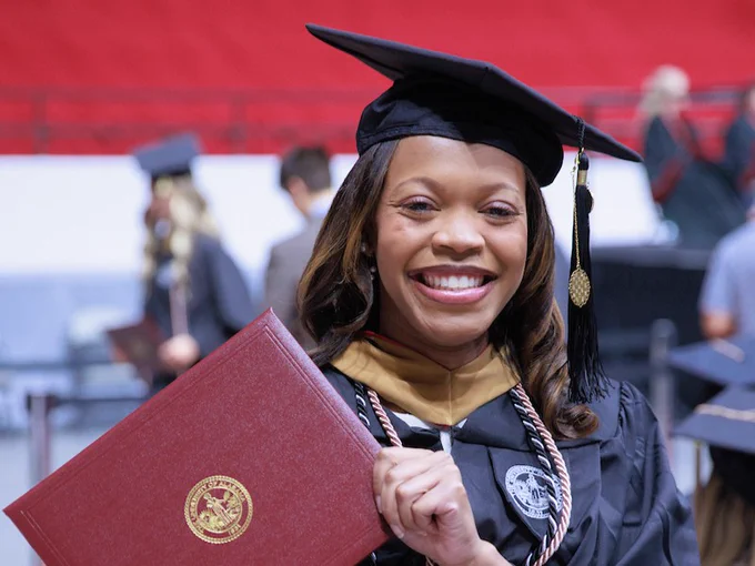 A graduate is seen showing off their diploma at Commencement. 