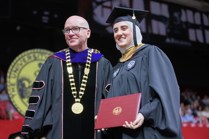 President Mohler poses for a photo with a graduate receiving a diploma during Commencement.