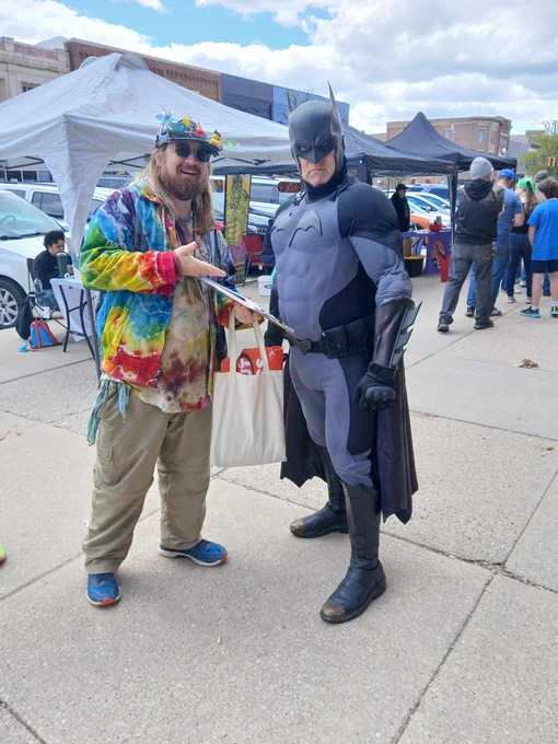 Colorfully dressed MMOP Circulator handing a petition clipboard to Batman!