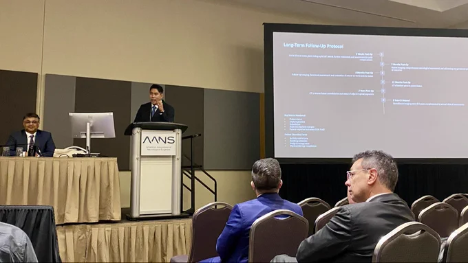 Jang Won Yoon, MD, presents his talk. The title of his slide reads, Long-term follow-up protocol. Praveen Mummaneni, MD, served as one of the moderator of the session.