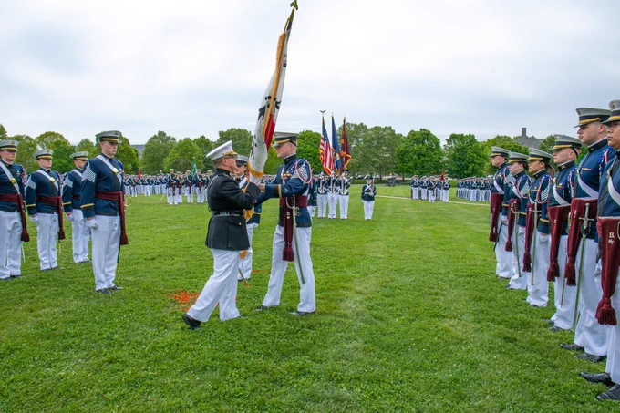  A Marine general and a cadet exchange a ceremonial flag during a change-of-command ceremony, surrounded by cadets in formation.