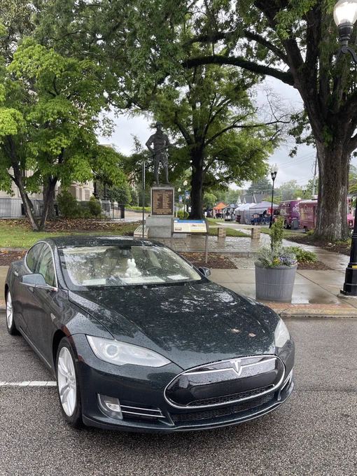 Saturday, May 2, 2026, downtown Smithfield, NC. Pictured left to right is a Metallic Sequoia Green 2012 Model S parked along the south side of East Market Street (US-70 Highway Business), in the closest spot to the row of food trucks. When I arrived they were still lining up cars along the north side of the street, but I would’ve backed into a big puddle, so I asked if I could start off the row for the south side. Only EV registered.