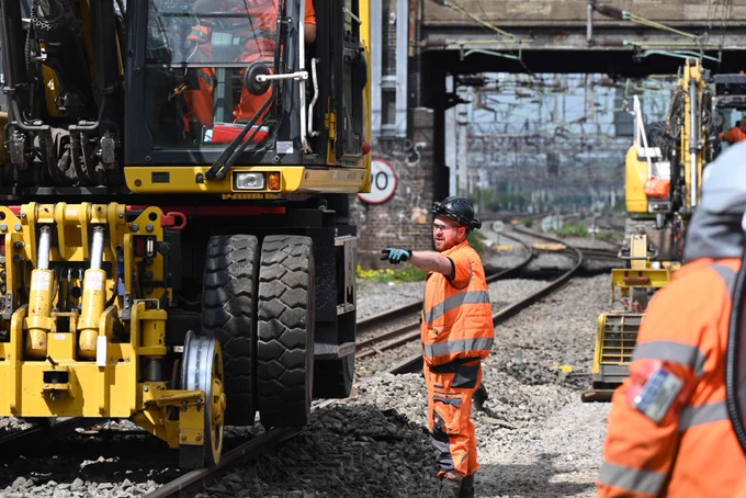 A track worker directs the plant machinery.