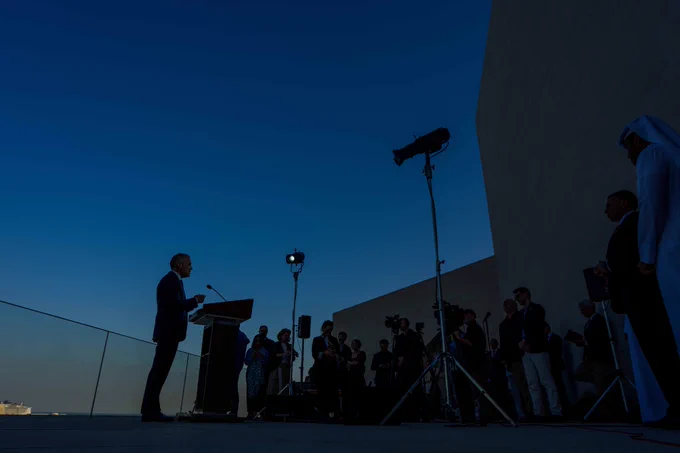 Prime Minister Mark Carney addresses media during an outdoor media availability, speaking to reporters as cameras. Lights frame the evening skyline.