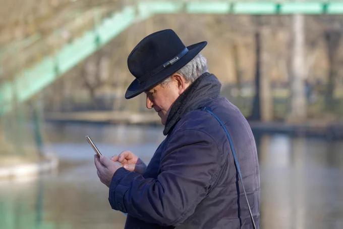 Older man with hat looking at his phone
