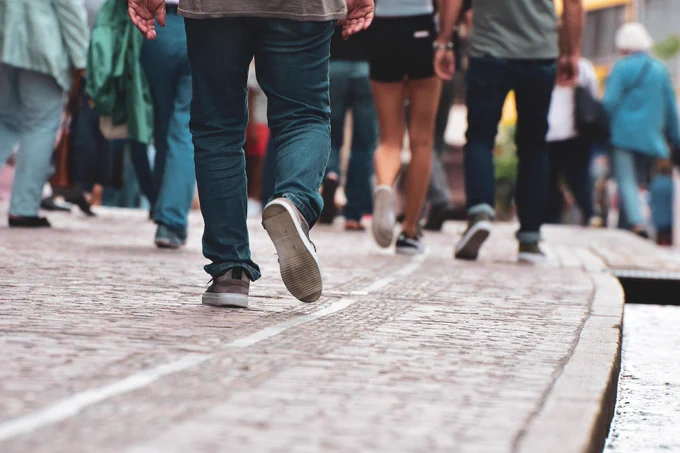 Low perspective street photo of many people's legs, walking on a pavement
