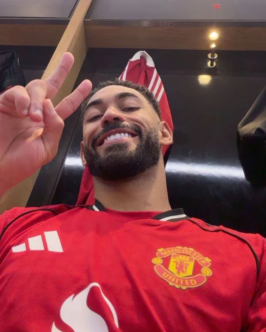 Matheus Cunha smiles while saluting the camera in a dressing-room selfie.
