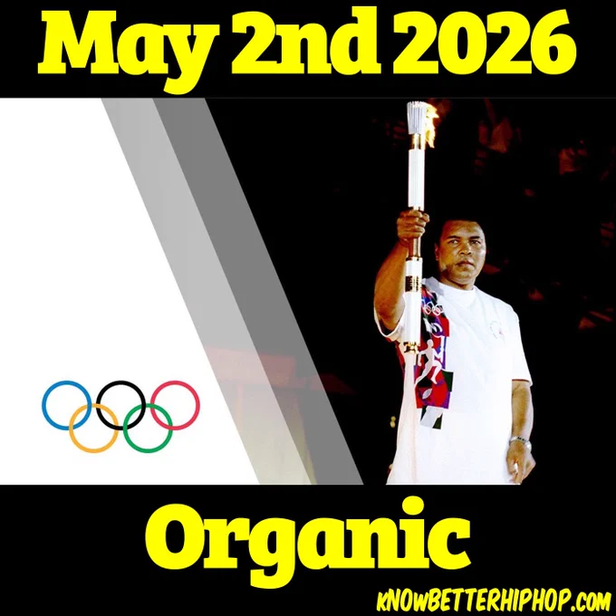 A graphic featuring a historic photograph of Muhammad Ali holding the lit Olympic torch high in the air, wearing a white Olympic-themed shirt against a dark background. The left side of the image is white with the five interlaced Olympic rings. The entire composition is framed by thick black horizontal bars at the top and bottom with bold yellow text. The top bar reads "May 2nd 2026," and the bottom bar features the word "Organic" with the website "KNOWBETTERHIPHOP.COM" in the bottom right corner.