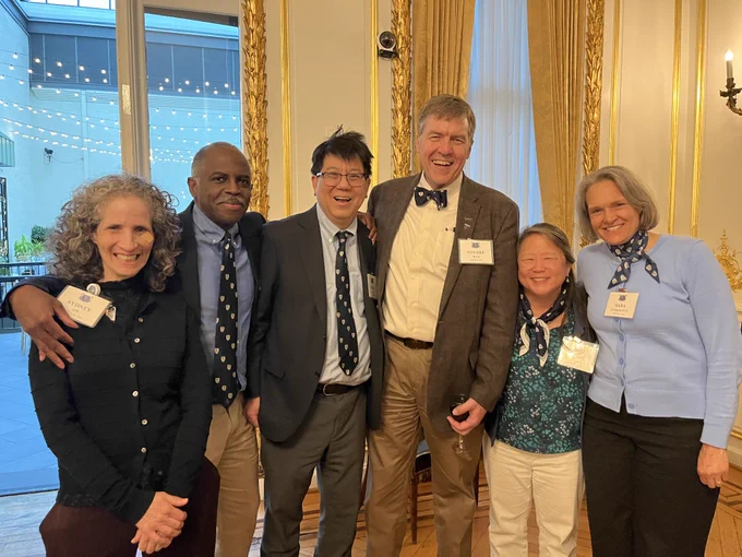 Six doctors, three women and three men, posing together joyfully