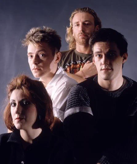 New Order in a 1988 studio portrait during the Blue Monday '88 era, with Bernard Sumner, Peter Hook, Stephen Morris and Gillian Gilbert arranged in a minimal, softly lit promotional image.