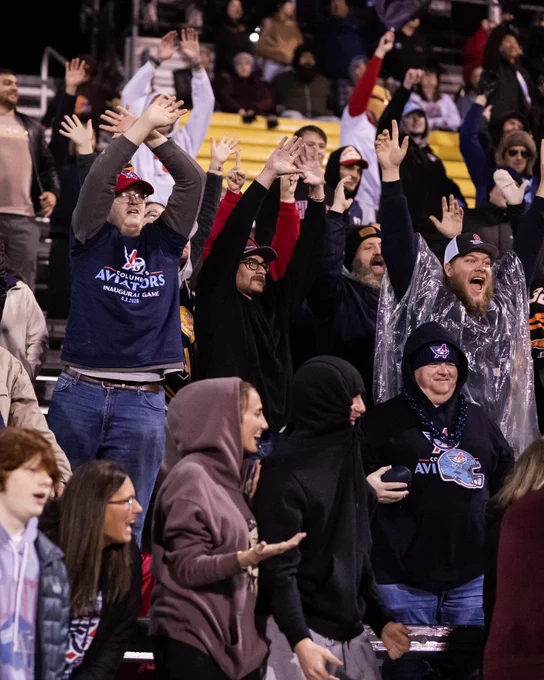 A group of enthusiastic fans cheer at a sporting event, displaying exhilaration and unity. The atmosphere is lively and vibrant.