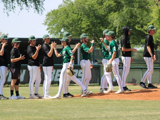 Dallas College Brookhaven baseball players celebrate a win over Dallas College Cedar Valley, exchanging high-five handshakes at the pitcher's mound. 