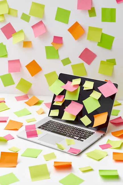 Laptop covered in sticky notes, with vibrant papers scattered around, captures creative chaos.