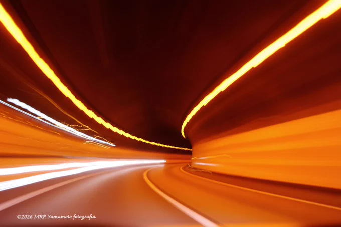 ALT : ⬇️  

A long-exposure action shot taken from a moving vehicle inside a tunnel. The interior is bathed in a warm orange glow, with the tunnel lights appearing as continuous streaks of light that follow the curve of the road.

Location: 東北自動車道 • 宮城県辺り

©2026 MRP. Yamamoto | photographié