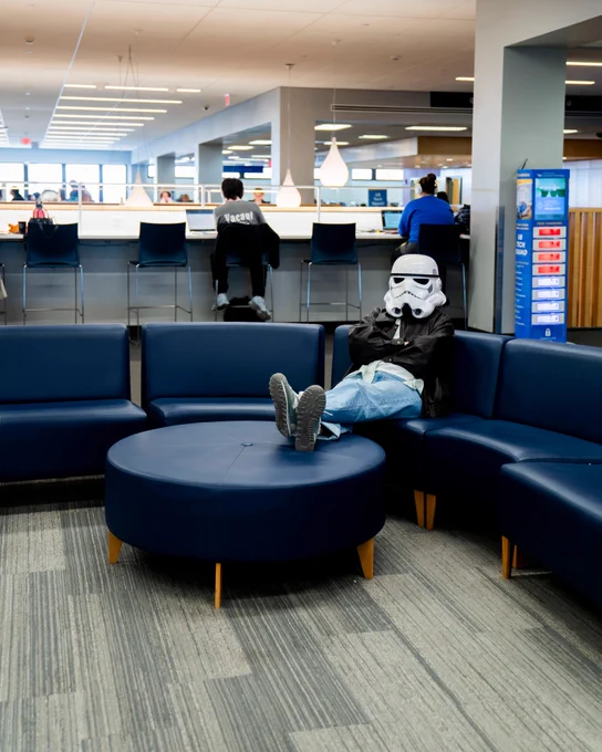 Student lounges on the library furniture wearing a Storm Trooper helmet