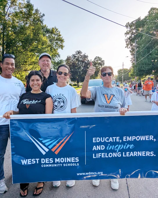 School Board members and others carry a WDMCS banner in the Homecoming parade.