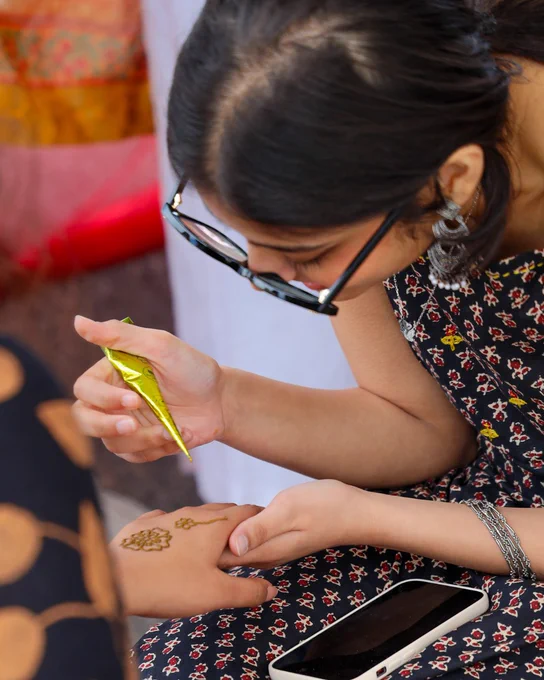 a woman sitting and doing henna