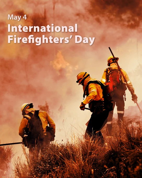 Text "May 4 International Firefighters' Day" sits over a backdrop of three firefighters coming down a slope covered in brush in full gear into a wall of smoke.