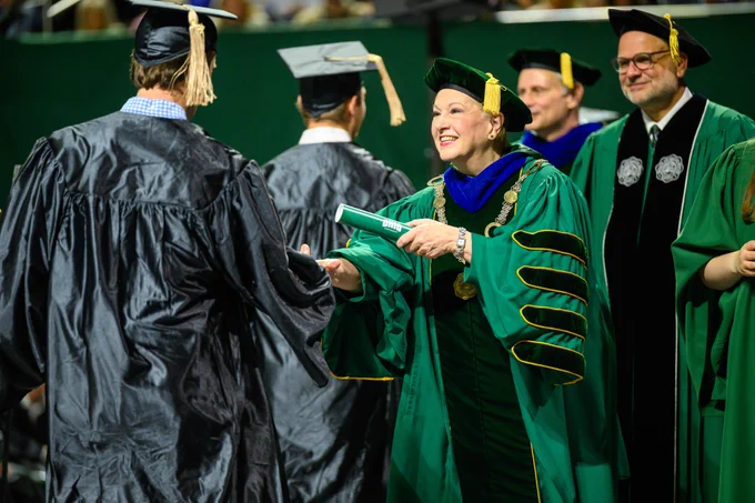 University president hands diploma to graduate.