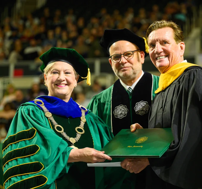 University president hands diploma to graduate.