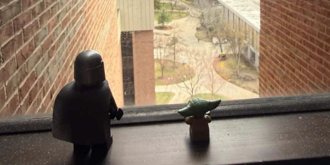 Lego Mandalorian and Baby Yoda figures look out at Michigan Tech’s campus from a window. 
