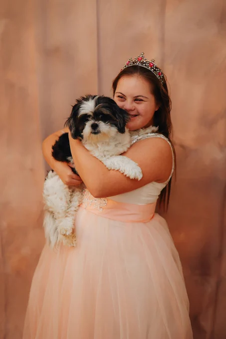 Girl with Down's Syndrome holding a black and white dog. Photo by Brooke Balentine.