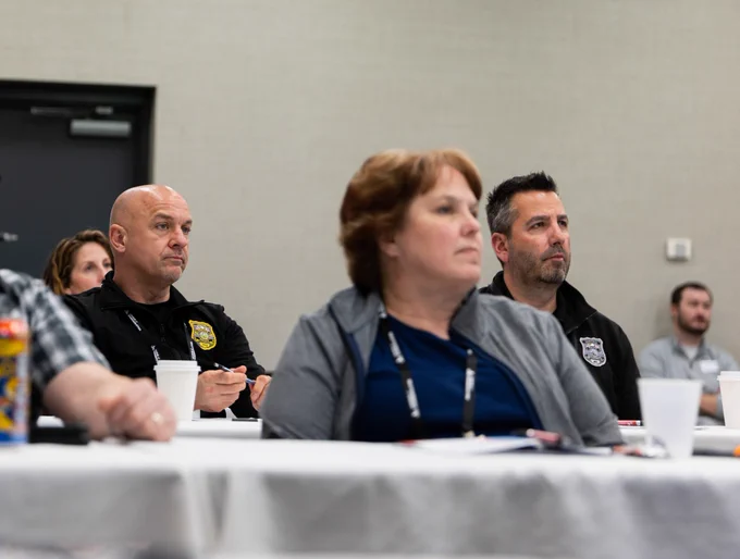 Group of adults attentively listening during a conference or training session in a meeting room.