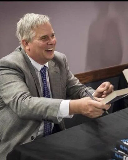 Male holding out a book and laughing