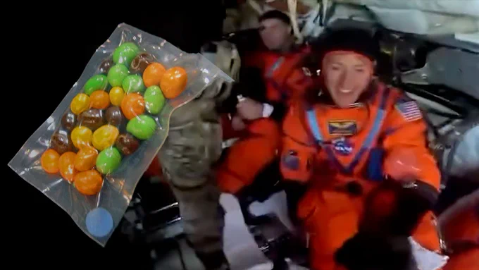 Montage of a video still and a photo depicting Peanut M&M's as they packed for spaceflight and Artemis II mission specialists Christina Koch and Jeremy Hansen inside their Orion spacecraft after returning from their flyby of the moon. (NASA/Smithsonian)