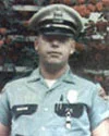 Blurry image of Preston Butler in a police uniform standing against a brick wall. 