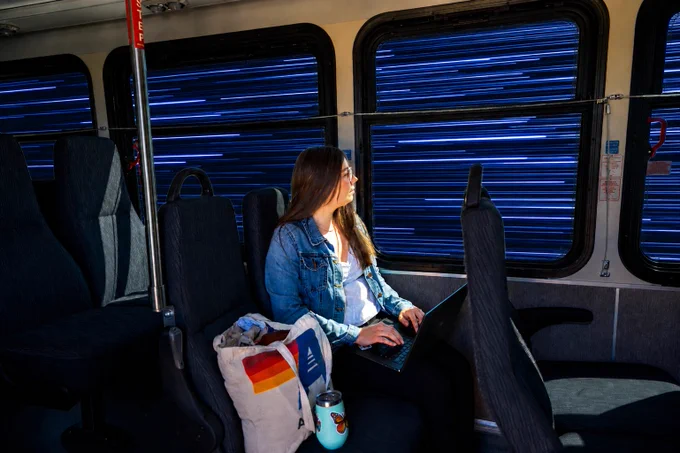 A woman sitting on a RFTA bus working on a laptop looks outside the windows as the bus jumps to lightspeed.