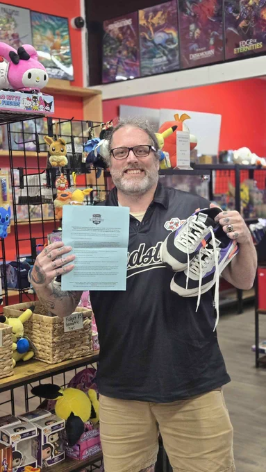 Joey holding his shoes and an RCQ invite paper after winning 
