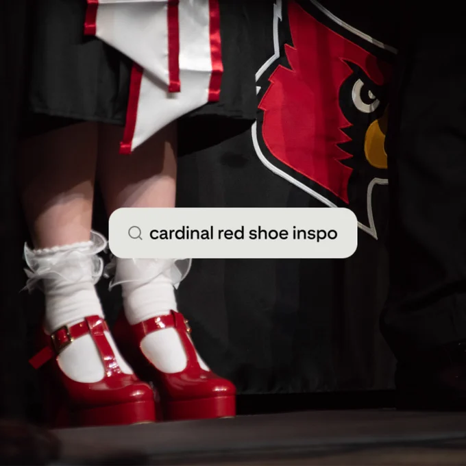 A close-up shot of a woman's lower legs and red heels with ruffled socks standing in front of a Louisville Cardinal logo background with a search bar screenshot over it that reads "cardinal red shoe inspo"