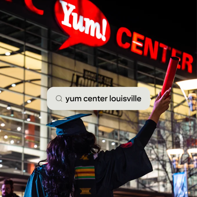 A UofL graduate standing in front of the Yum! Center holding her red diploma tube in the air with a search bar screenshot over it that reads "yum center louisville"