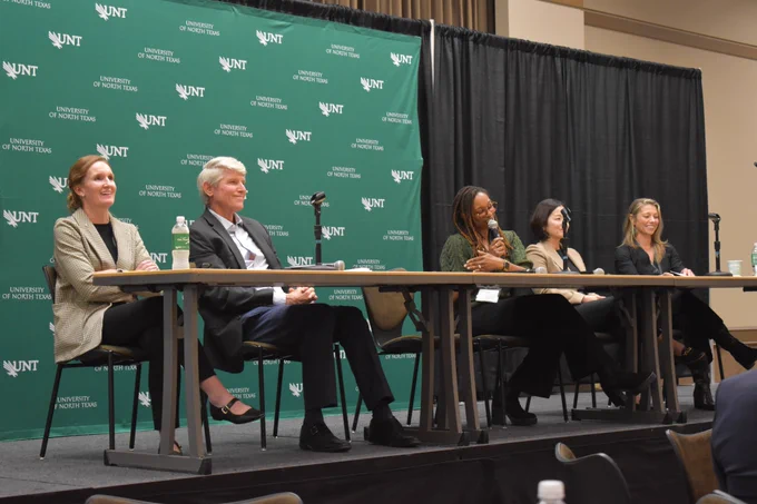 LEEF co-directors April Prince, Michael Monticino, Yolanda Mitchell, Yunjo An and Carrie Allen sit behind a table on a stage as Mitchell speaks into a mic.