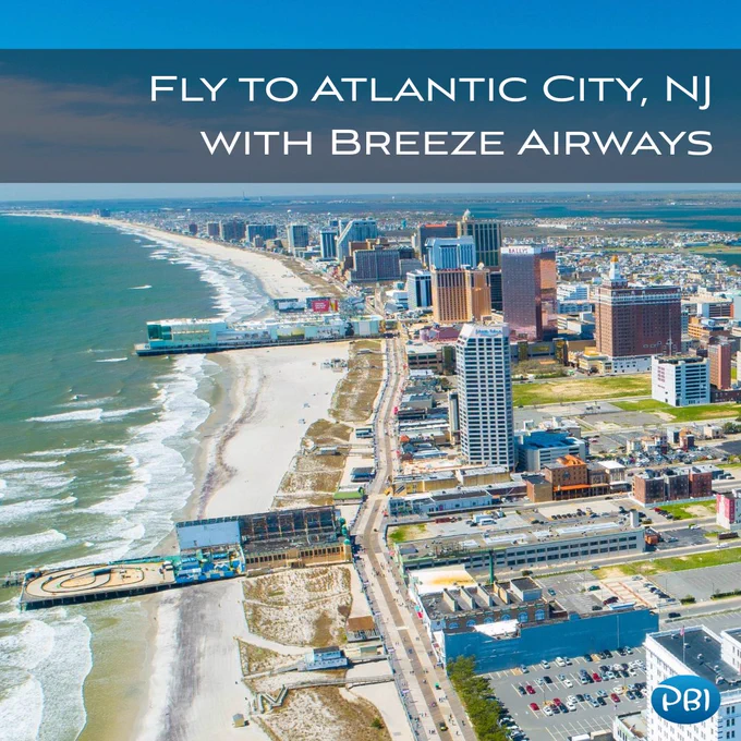 Aerial view of Atlantic City, New Jersey showing coastline, sandy beach and ocean waves beside hotels and casinos. The boardwalk runs parallel to the beach with a pier extending into the ocean. Overlay text reads “Fly to Atlantic City, NJ with Breeze Airways,” with a PBI logo in bottom right.