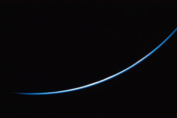 A sliver of the edge of Earth glows blue against the vast darkness of space. Credit: NASA