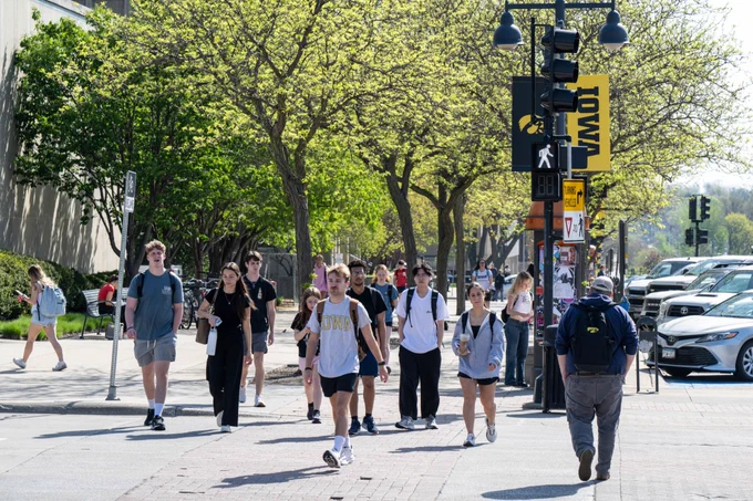 An image of people in a cross walk in downtown Iowa City.