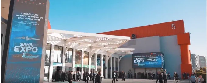 Crowd gathering outside a modern expo center with large digital banners promoting SAHA EXPO under a clear blue sky. 
Photo credit: Saha Expo 2026