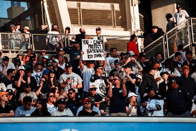 Sign in the bleachers reads "You can't predict baseball. RIP John" 