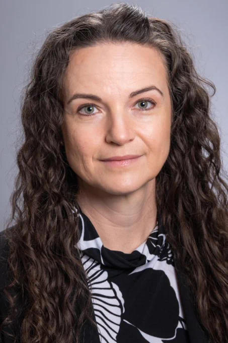Angela Carter, Ph.D, stands in front of a gray background.