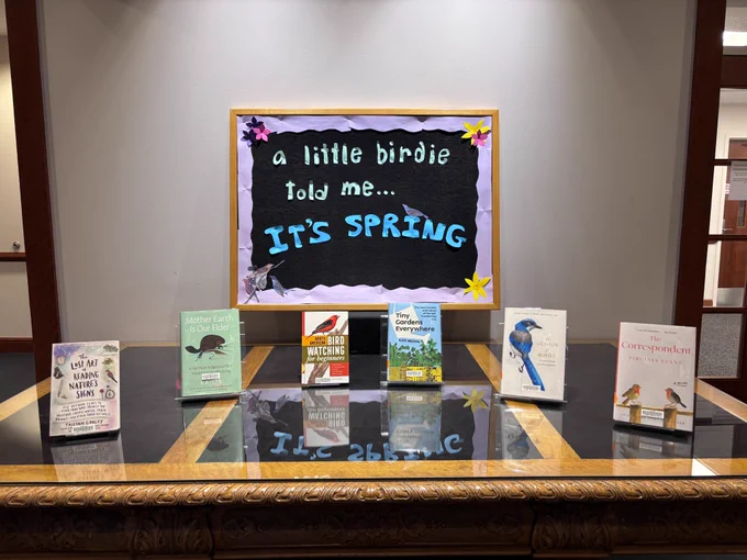 A book display with 6 books: The Lost Art of Reading Nature’s Signs by Tristan Gooley, Mother Earth is our Elder by Katłįą, North American Bird Watching For Beginners by Sharon Stiteler, Tiny Gardens Everywhere by Kate Brown, The Genius of Birds by Jennifer Ackerman, and The Correspondent by Virginia Evans. Signage reads, “a little birdie told me… it’s spring.”