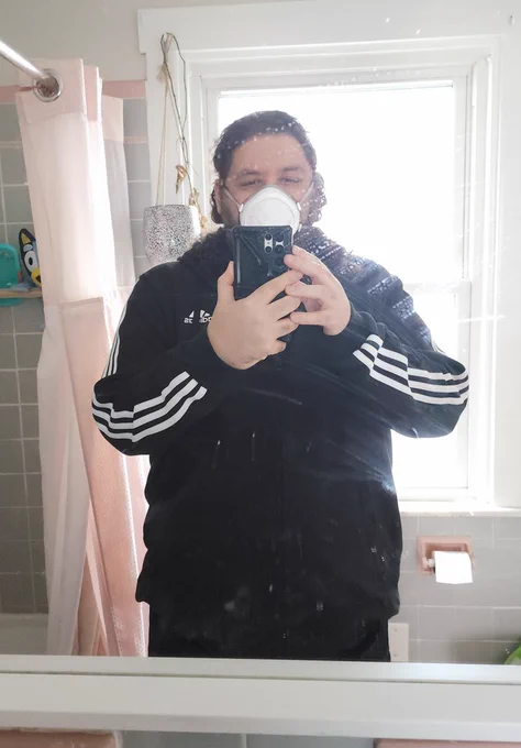 Mirror selfie of me wearing a flomask and an Adidas jumper in a slightly messy bathroom