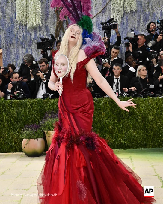 Gwendoline Christie poses in a red dress, holding a mask, at the 2026 Met Gala. 