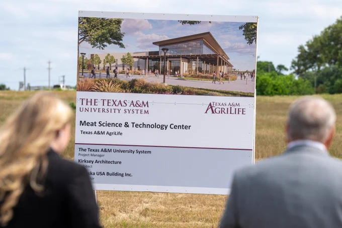 A sign on a grassy area displays a rendering of the Texas A&M University System's Meat Science & Technology Center.