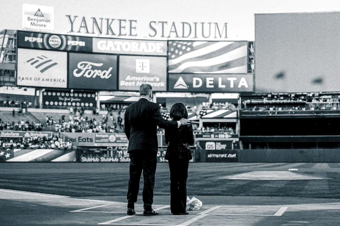 Michael Kay and Suzyn Waldman stand during a moment of silence in memoriam of John Sterling after placing flowers on home plate at Yankee Stadium. 